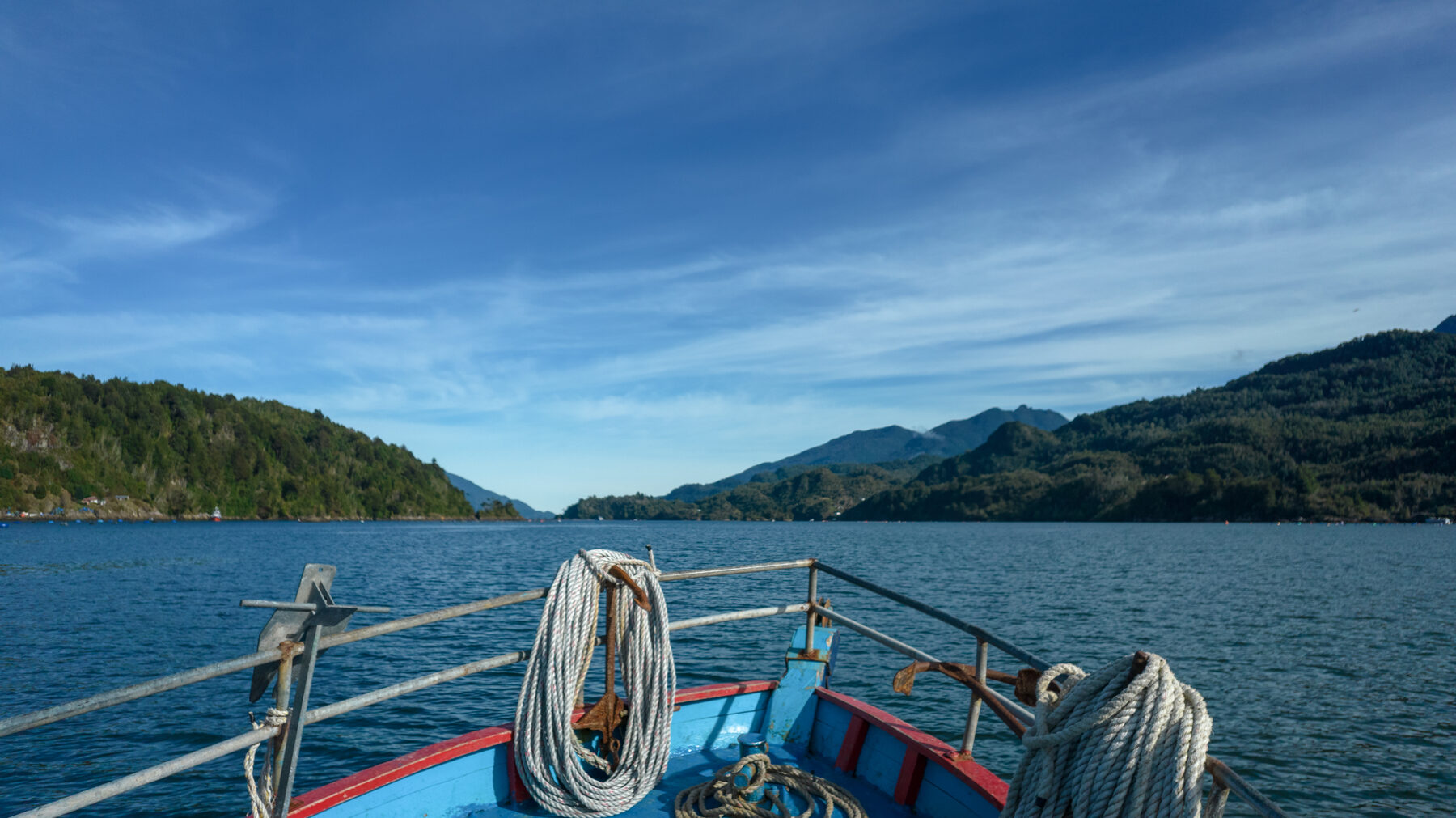 Proa de bote navegando entre cerros boscosos